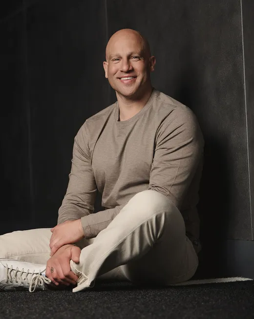 Jeff Halevy seated against a dark wall, smiling